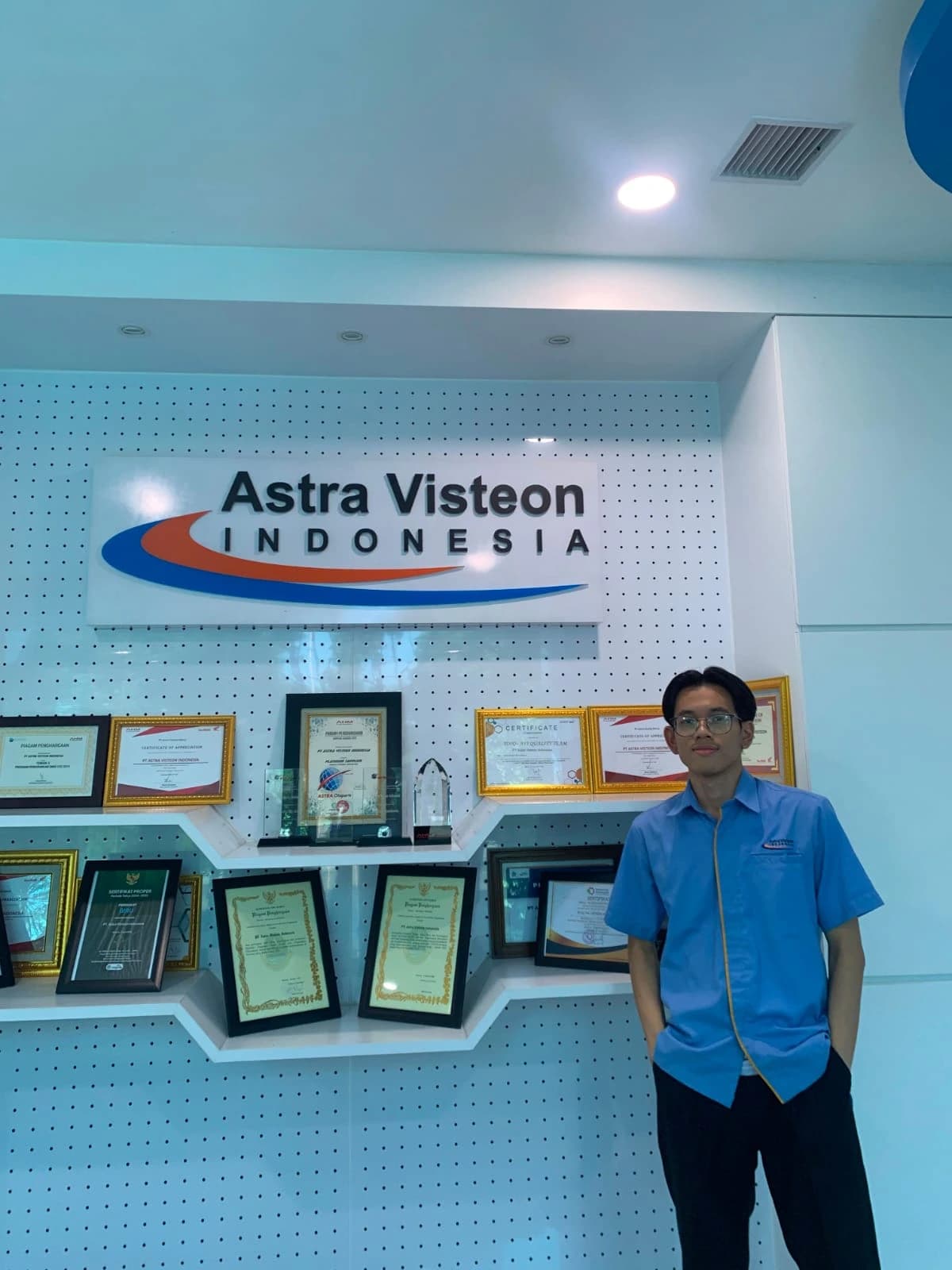 Felix at Astra Visteon Indonesia beside a display of certificates